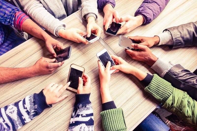 Top view hands circle using phone in cafe - Multiracial friends mobile addicted interior scene from above - Wifi Connected people in bar table meeting - Concept of teamwork main focus on left phones