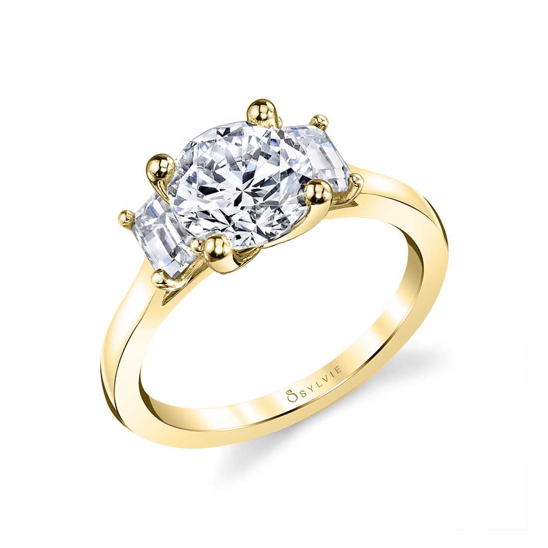 three stone engagement ring with emerald cut side stones in yellow gold